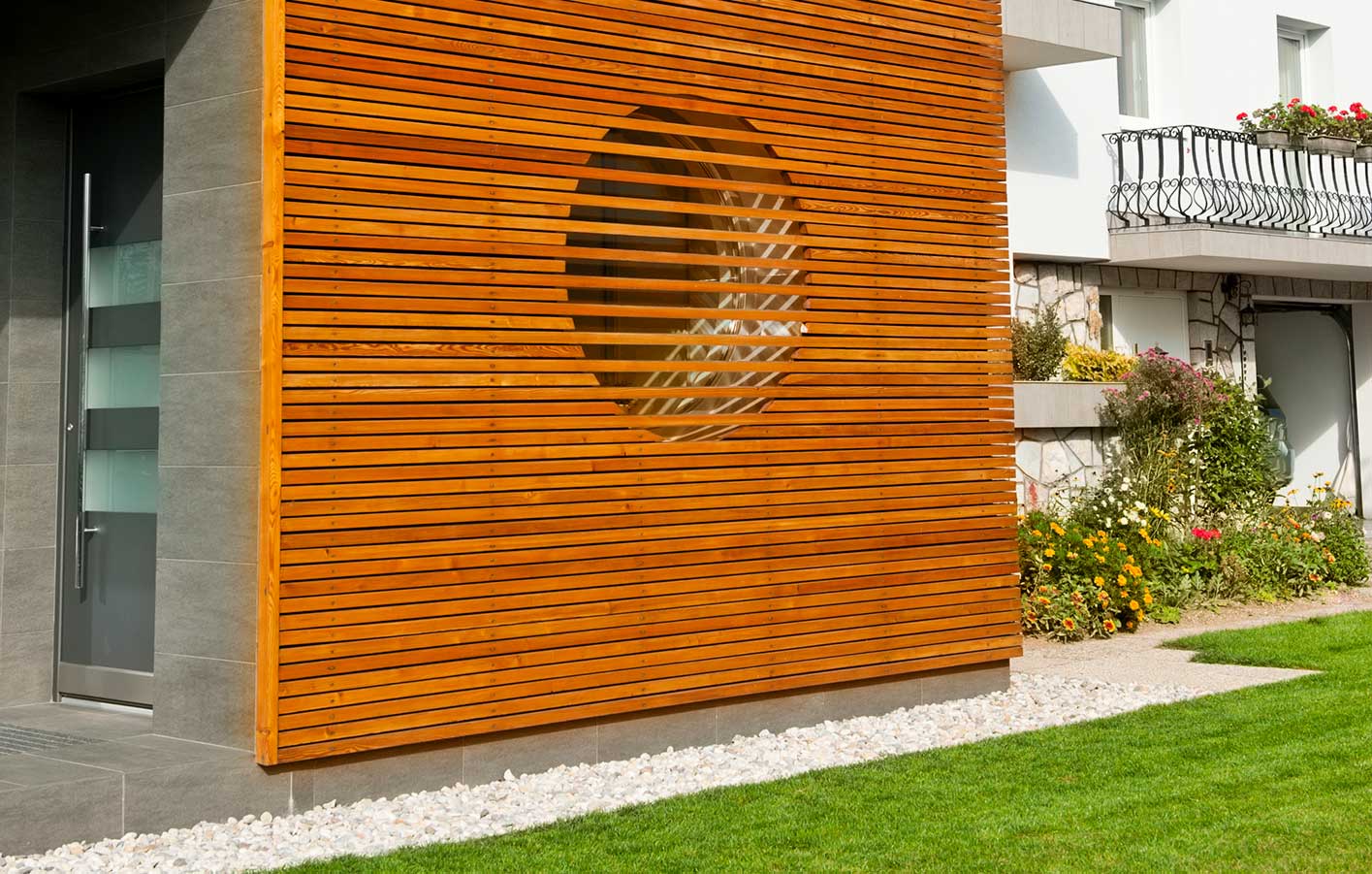 Moderne Hausfassade mit horizontal angeordneten Holzprofilen und integriertem Sichtschutz