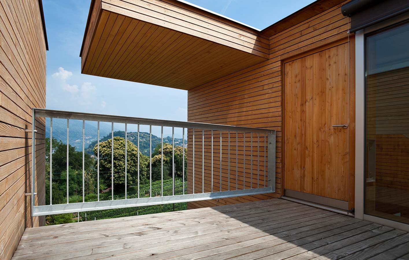 moderne Holzfassade mit Balkon und einem Ausblick ins Grüne
